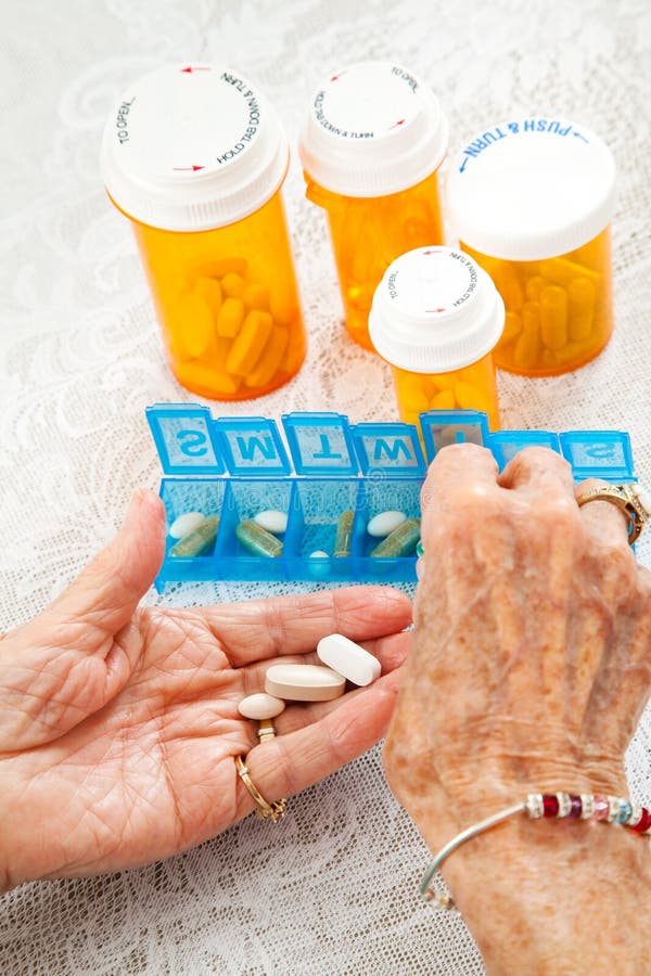 Closeup of an elderly woman's hands sorting her medication for the week. Closeup of an elderly woman's hands sorting her medication for the week.