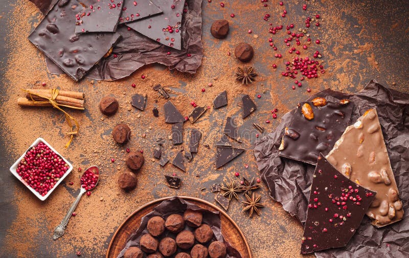 Assortment of chocolate bars, truffles, spices and cocoa powder on dark background. Space for text, top view. Assortment of chocolate bars, truffles, spices and cocoa powder on dark background. Space for text, top view