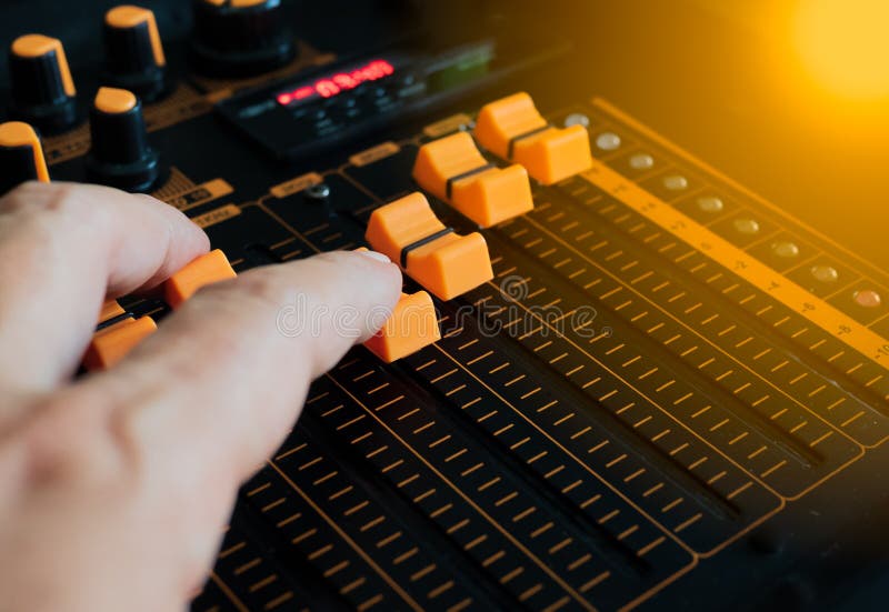 The sound mix button is being adjusted by the hands of the sound engineer. To match the music the composer has composed stock photos