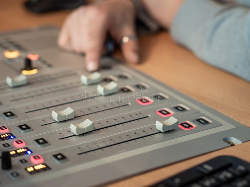 Sound technician adjusts audio levels on mixing console in a recording studio during a busy session royalty free stock image
