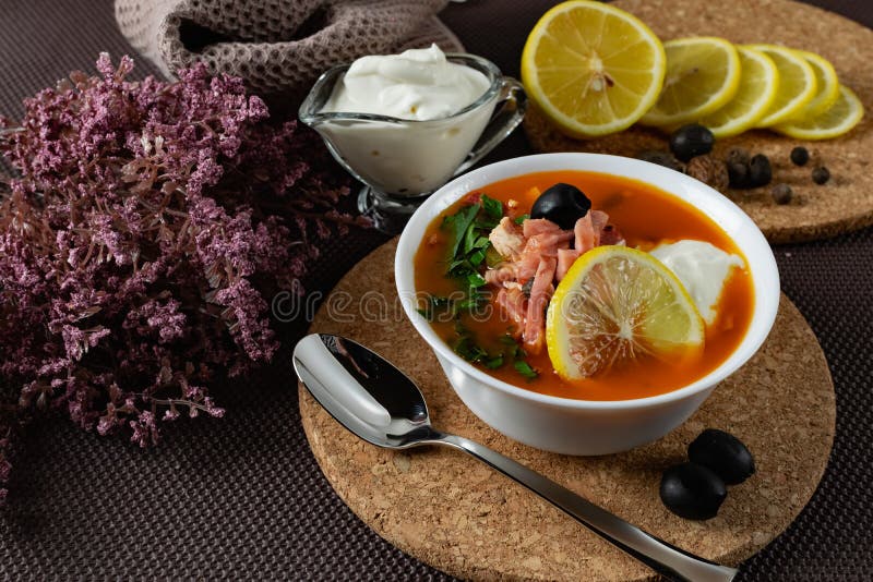 Soup Solyanka is a combined meat soup with smoked meat , various types of meat and tomato paste, serving dishes with sour cream, l