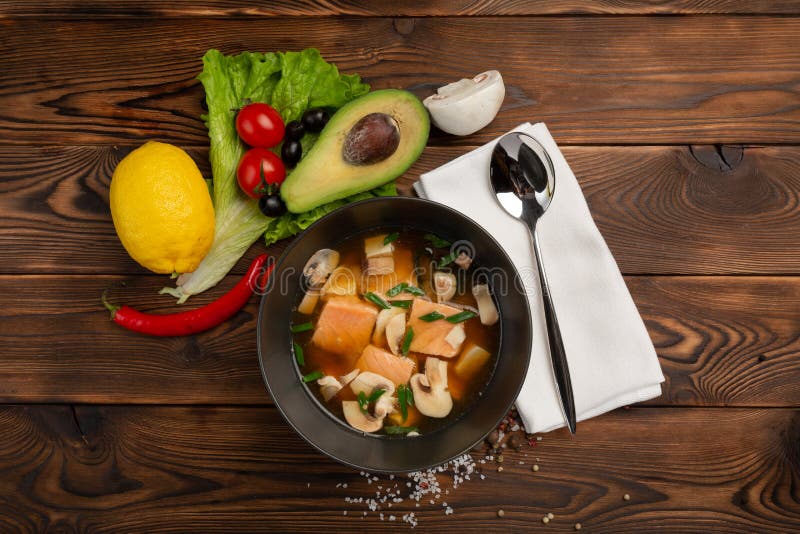 Soupe chinoise avec les poissons rouges dans un plat noir sur un fond en bois photographie stock libre de droits Soupe chinoise avec les poissons rouges dans un plat noir sur un fond en bois photographie stock libre de droits