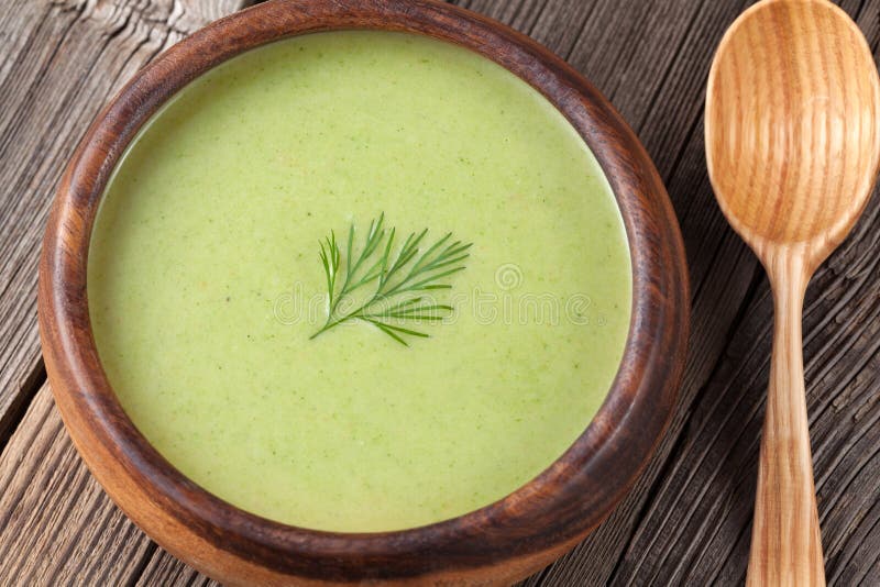 Green broccoli cream soup in a wooden bowl with spoon on vintage background. Green broccoli cream soup in a wooden bowl with spoon on vintage background