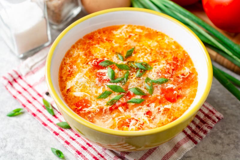 Soupe à baisse d'oeufs de chinois traditionnel avec la tomate et l'oignon vert dans la cuvette sur le fond en pierre gris images stock Soupe à baisse d'oeufs de chinois traditionnel avec la tomate et l'oignon vert dans la cuvette sur le fond en pierre gris images stock