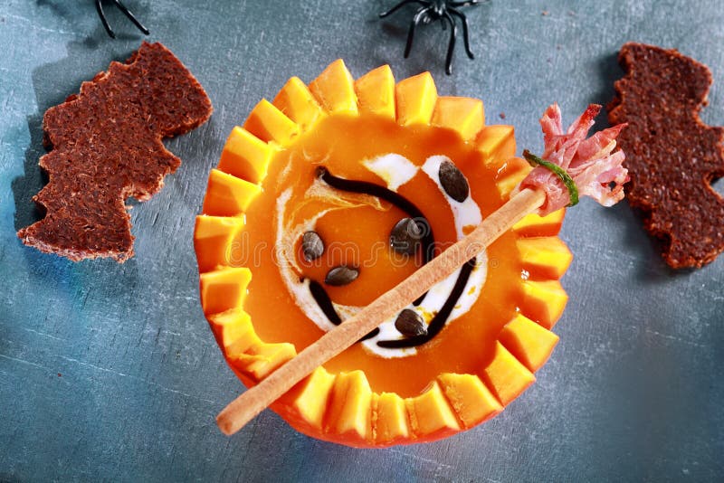 Halloween Pumpkin Soup Served in Half a Pumpkin with Bat Shaped Crouton Toasts and Broomstick Bread Stick from Above. Halloween Pumpkin Soup Served in Half a Pumpkin with Bat Shaped Crouton Toasts and Broomstick Bread Stick from Above