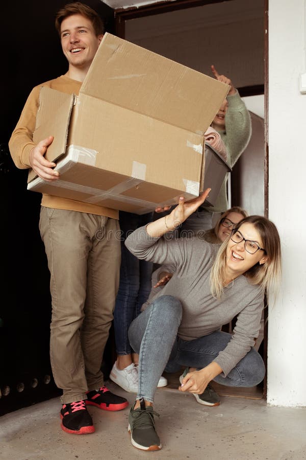 Souriant vertical jeunes élèves communicatifs joyeux sortant boîte en carton. début de l'éducation pour les élèves de première ann. Souriant vertical jeunes élèves communicatifs en train de sortir des boîtes en carton debout près de la porte d'entrée. déménagement du nouveau campus universitaire. début de l'éducation pour les étudiants de première année vie collégiale