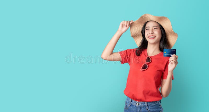 Sourient heureusement la bonne peau de femme asiatique tenant la carte de crédit et regardant en avant sur le fond bleu avec l'es images stock Sourient heureusement la bonne peau de femme asiatique tenant la carte de crédit et regardant en avant sur le fond bleu avec l'es images stock