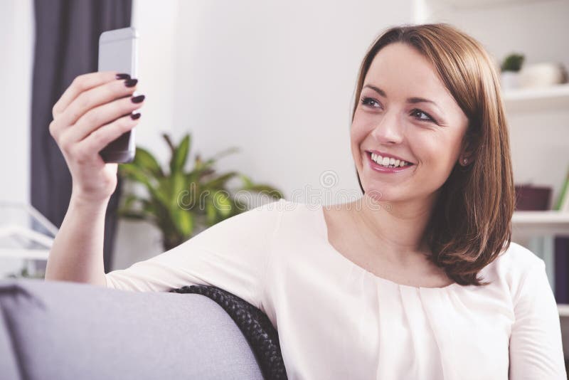 Sourire se reposant de fille d'une chevelure brune heureuse sur un sofa image libre de droits Sourire se reposant de fille d'une chevelure brune heureuse sur un sofa image libre de droits