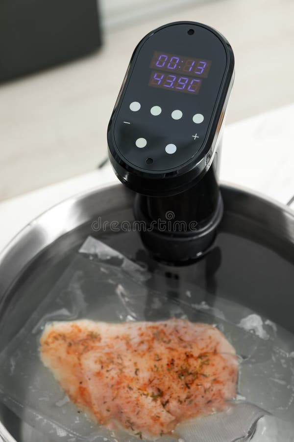 Sous Vide Cooker and Vacuum Packed Meat in Pot on Table, Closeup