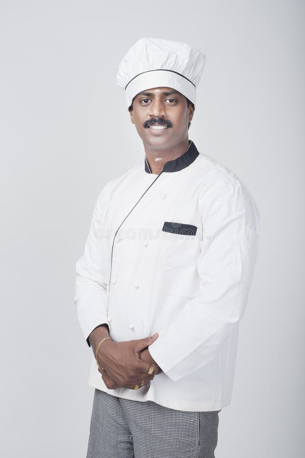 South Indian chef standing with his hands clasped and smiling