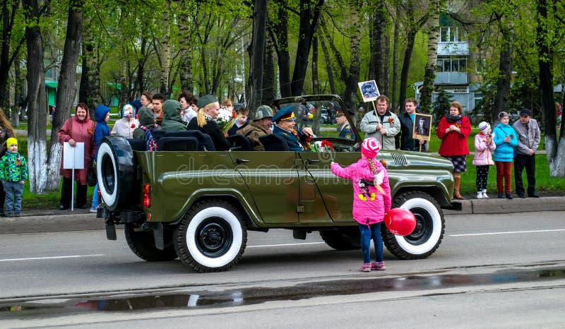 Sovjet militaire suv, het meisje geeft de bloem aan de oorlogsveteraan De mensen bevinden zich met foto's en vieren de overwinnin stock foto's Sovjet militaire suv, het meisje geeft de bloem aan de oorlogsveteraan De mensen bevinden zich met foto's en vieren de overwinnin stock foto's