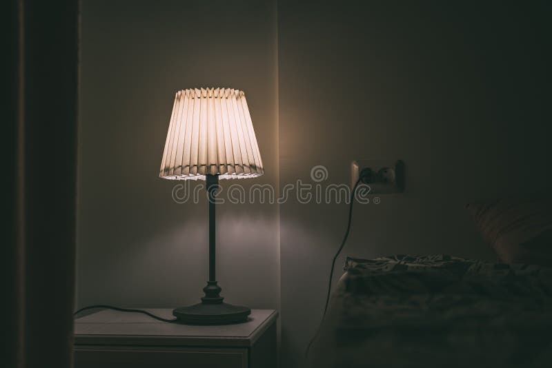 Sovrumlampa på natttabellen i hotellrum på natten arkivbild Sovrumlampa på natttabellen i hotellrum på natten arkivbild