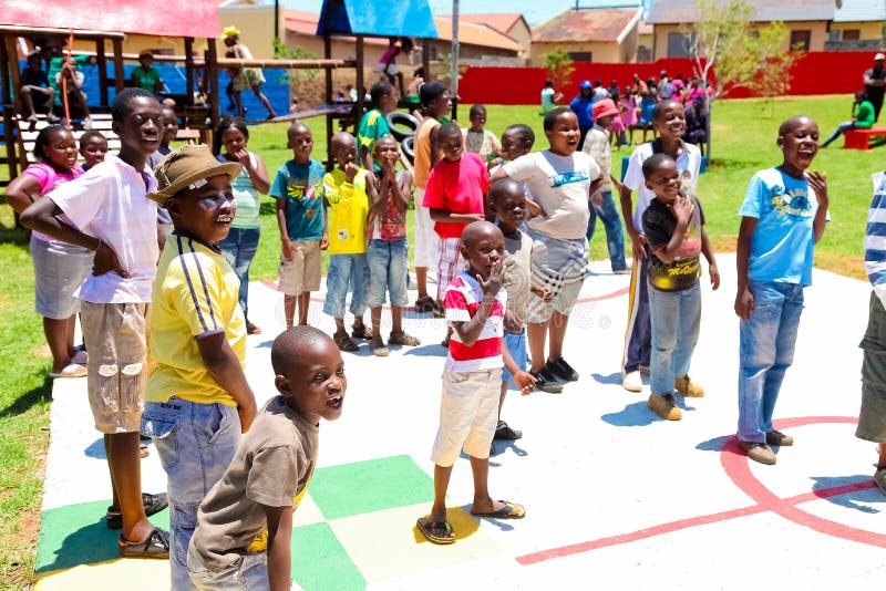 African children lining up to take turns to take a goal shot on public playground basketball court