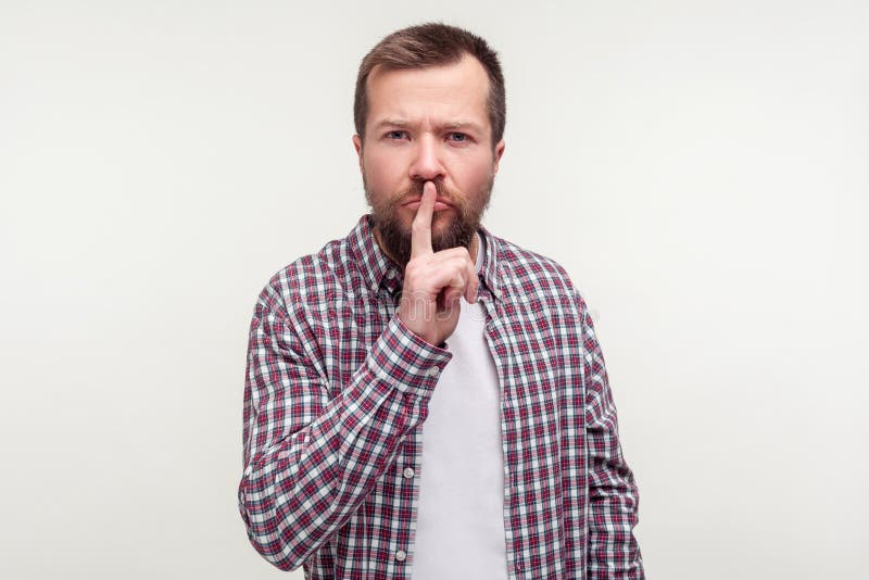 Soyez calme! Portrait de l'homme barbu sérieux strict faisant le geste de silence de silence avec le doigt sur les lèvres. Fond bl image libre de droits