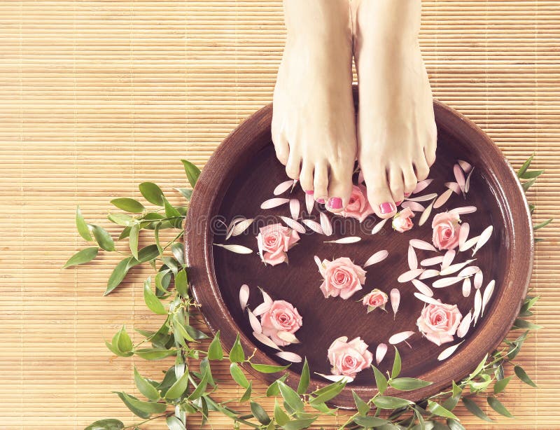 Spa background of beautiful female feet, flowers and petals