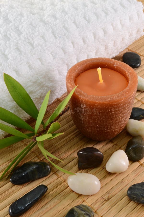 Immagine del concetto di spa con la candela, asciugamani, foglie e pietre.