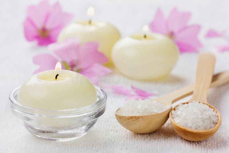 Spa composition with sea salt bath in wooden spoon, pink flowers and burning candles on a white surface royalty free stock photo Spa composition with sea salt bath in wooden spoon, pink flowers and burning candles on a white surface royalty free stock photo