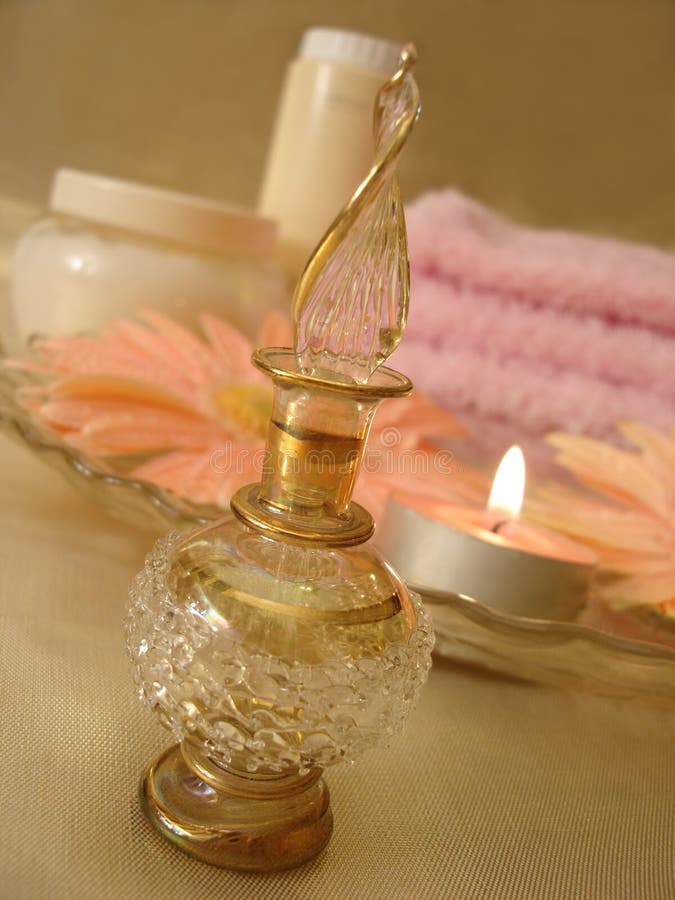 Spa essentials (beautiful bottle of perfume and candle, flowers, cream, towel on a background)