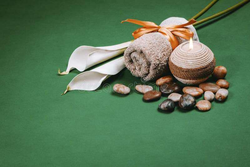 Spa essentials candela assorbente e fiori su sfondo verde scuro immagine stock