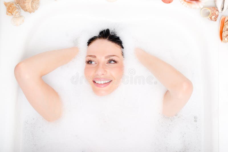 Spa fun: beautiful blue eyes brunette girl attractive young woman relaxing plunged into the foam and happy smiling portrait