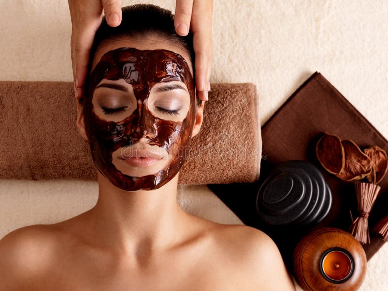 Spa massage for young woman with facial mask on face - indoors. Spa massage for young woman with facial mask on face - indoors