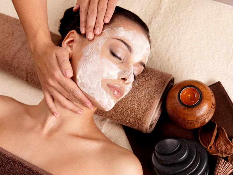 Spa massage for young woman with facial mask on face - indoors. Spa massage for young woman with facial mask on face - indoors