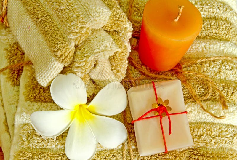 Spa products with flower and candle on towel