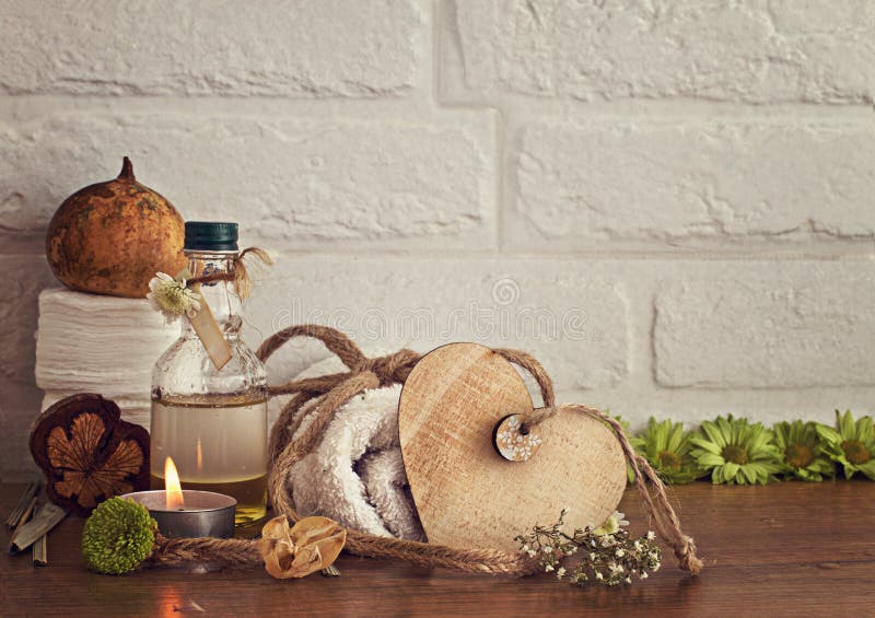 Spa setting with towels, oil and wooden heart on white bricks background