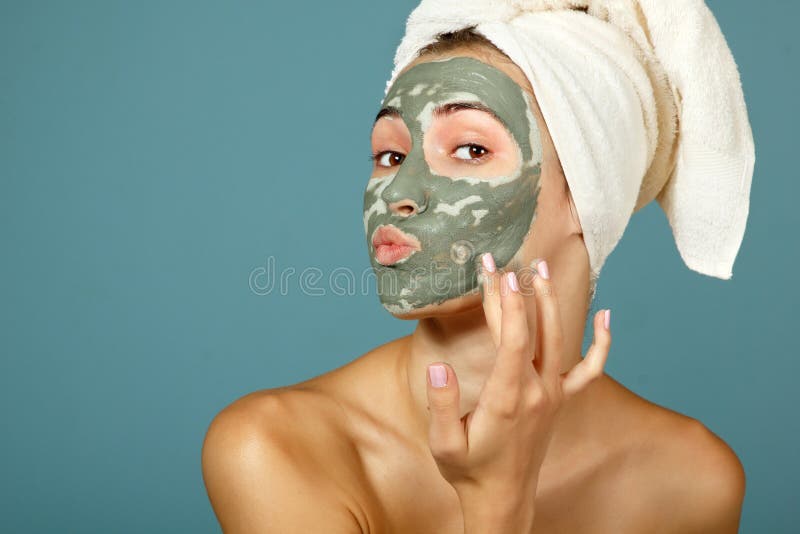 Spa teen girl applying facial clay mask. Beauty treatments. Over blue background. Spa teen girl applying facial clay mask. Beauty treatments. Over blue background.