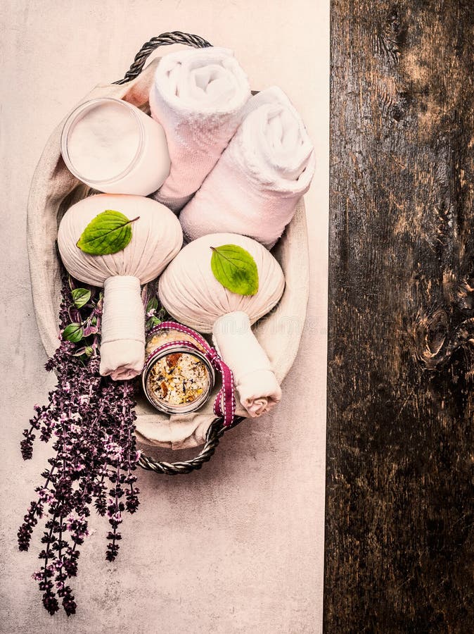 Spa or wellness background with herbal massage compress balls , towel , salt and fresh herbs in basket on wooden background