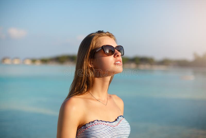 Spa wellness beach beauty woman in bikini swimwear relaxing and sun bathing near blue lagoon. Beautiful peaceful young