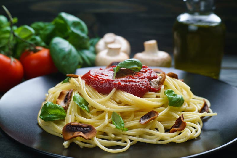 Spagettipasta med tomatsås, grillade champignons och basilika royaltyfri foto Spagettipasta med tomatsås, grillade champignons och basilika royaltyfri foto