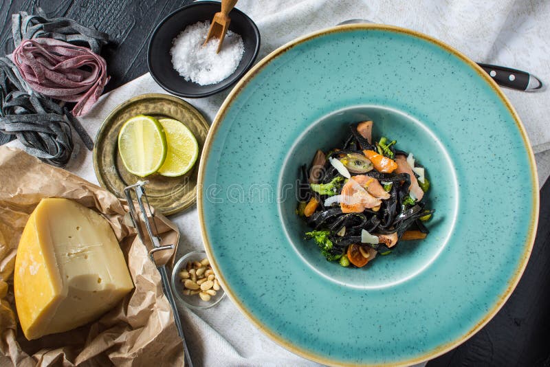 Spaghetti del nero dell'inchiostro della seppia con il salmone e le verdure immagini stock Spaghetti del nero dell'inchiostro della seppia con il salmone e le verdure immagini stock