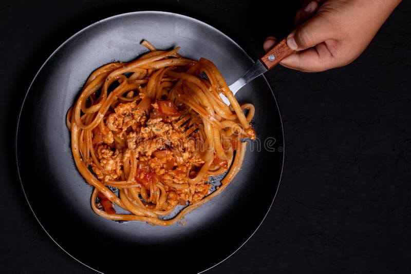 Spaghetti with Tomato Sauce and Minced Chicken. the Hand is Holding a