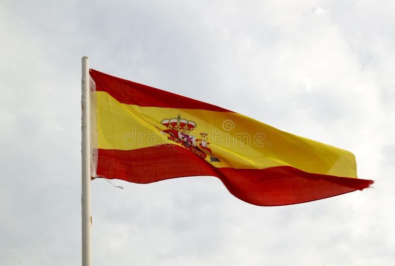 Spain flag on a blue sky with clouds background