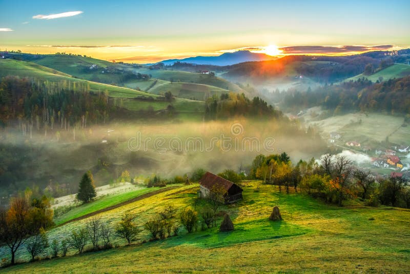 Spaltungslicht des schönen der Landschaftslandschafts-Rumänien-Dorfgebirgshügelfelder nebeligen Strahls des Vormittags ersten