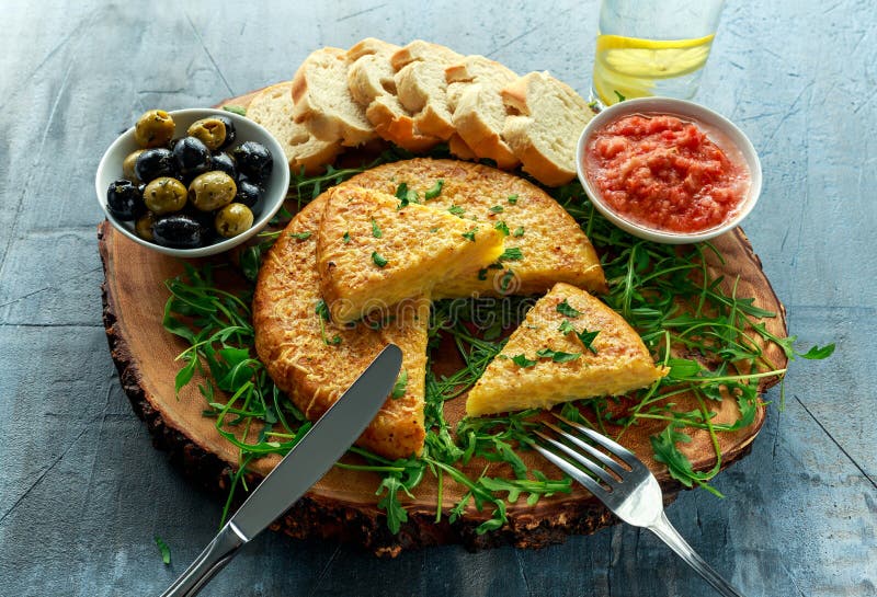 Spanish classic tortilla with potatoes, olives, tomatoes, rucola, bread and herbs.