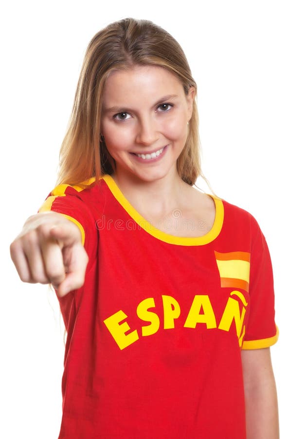 Beautiful woman with long blond hair in a spanish football jersey pointing at camera on a white background. Beautiful woman with long blond hair in a spanish football jersey pointing at camera on a white background