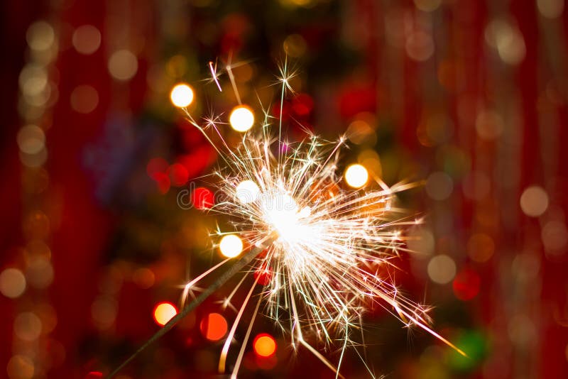 Sparklers near the Christmas tree with a red background