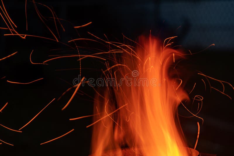 Sparks and flame erupt from the top of a chimney starter fire on a backyard grill royalty free stock photos