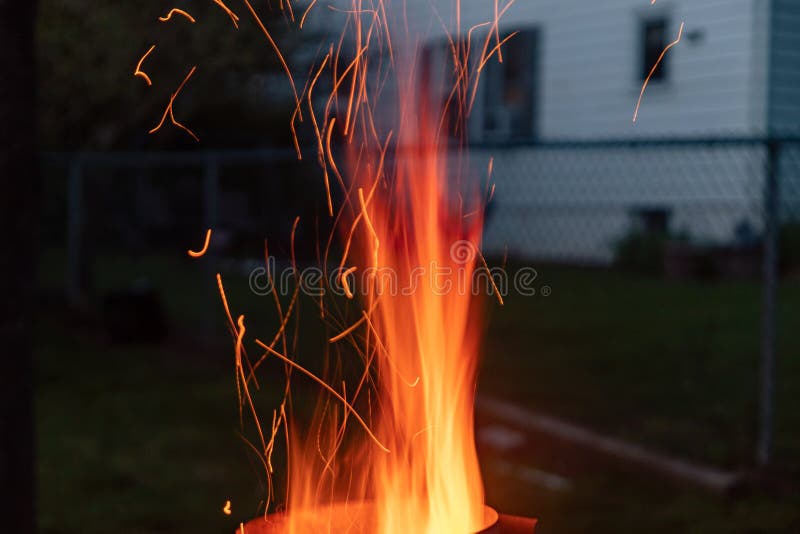 Sparks and flame erupt from the top of a chimney starter fire on a backyard grill royalty free stock photos