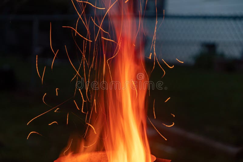 Sparks and flame erupt from the top of a chimney starter fire on a backyard grill stock image