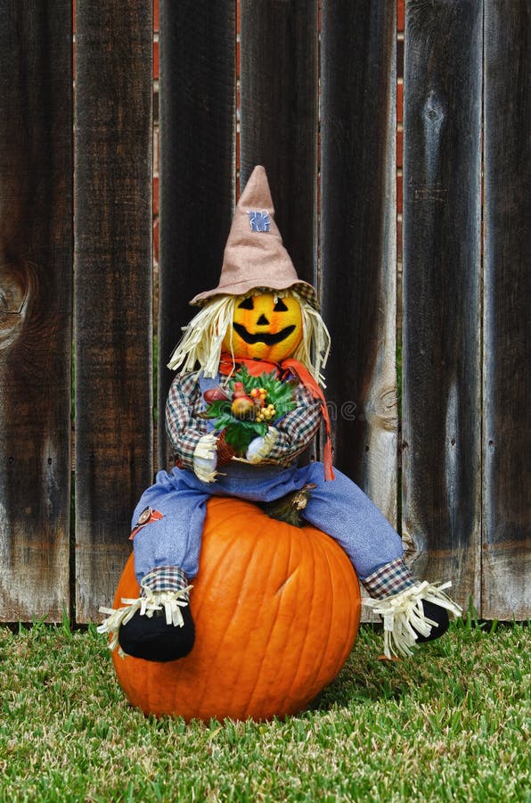 Spaventapasseri che si siede sulla zucca fotografia stock Spaventapasseri che si siede sulla zucca fotografia stock
