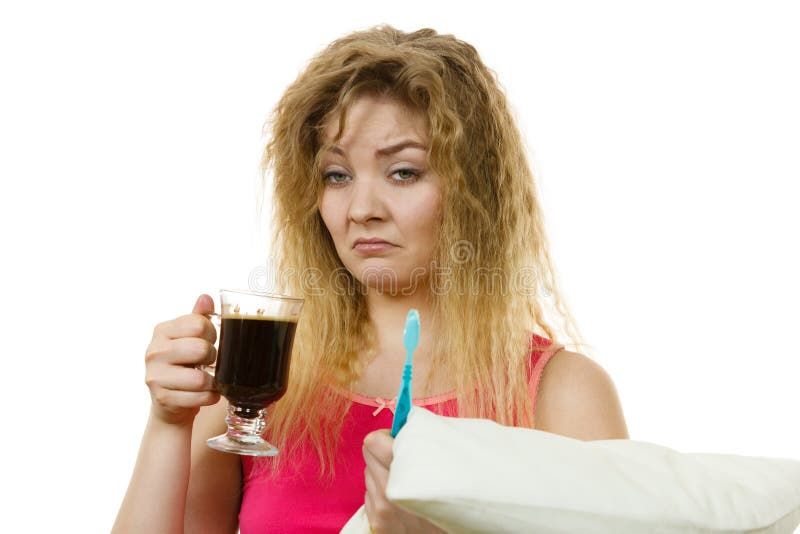 Donna stanca che tiene uno spazzolino da denti e un caffè fotografia stock libera da diritti