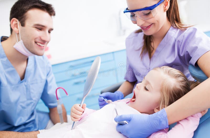 Specchio della tenuta della bambina ai dentisti immagine stock