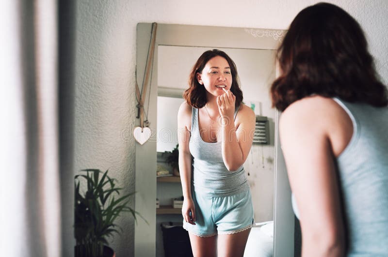 Specchio di bellezza e donna in camera per rossetto con cosmetica naturale e routine mattutina a casa. rifinitura. riflesso di trucco e donna con un'ispezione visiva per il trattamento della pelle in appartamento.