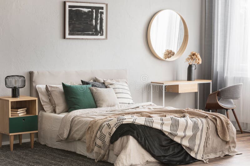 Specchio rotondo elegante nel telaio di legno sopra la tavola di console operata con i fiori in vaso in camera da letto d'avangua fotografia stock