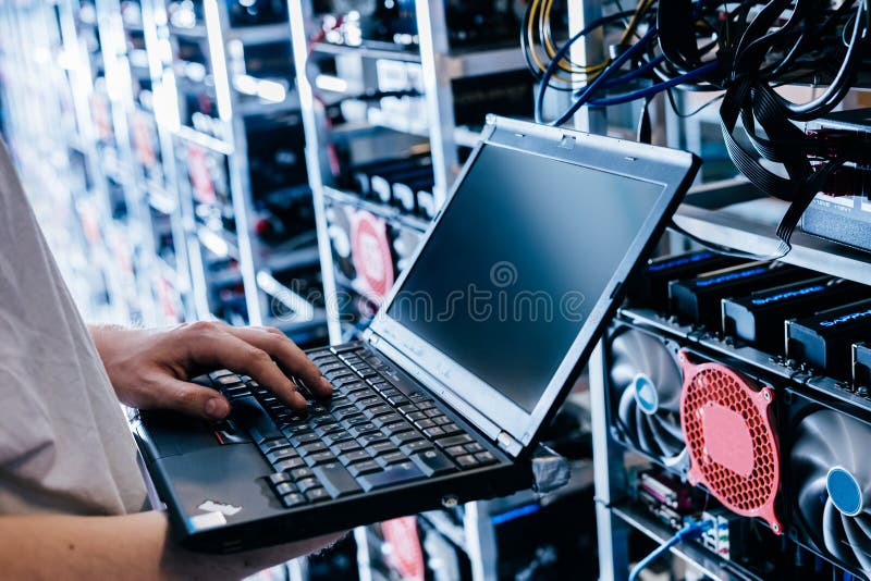 IT specialist working on computer in bitcoin and crypto currency mining farm stock photo