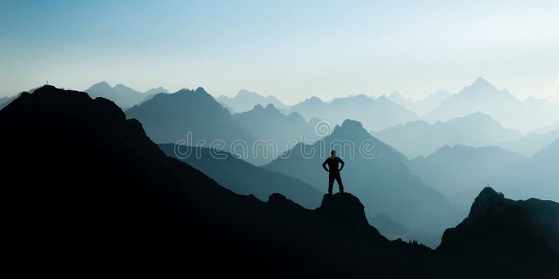Spectacular mountain ranges silhouettes. Man reaching summit enjoying freedom.
