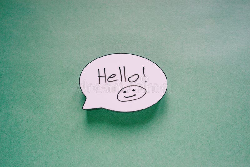 Speech bubble sign with the words Hello and Smiley. Speech message symbol on paper green background. Greeting card or invitation royalty free stock image Speech bubble sign with the words Hello and Smiley. Speech message symbol on paper green background. Greeting card or invitation royalty free stock image